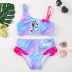 Load image into Gallery viewer, Two-piece swimsuit with mermaid scale design and 'Bluey' branding, surrounded by decorative items on a light background.
