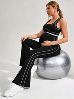 Load image into Gallery viewer, Woman sitting on an exercise ball wearing a black athletic outfit with white stripes.

