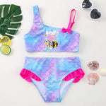 Load image into Gallery viewer, Mermaid-themed children's swimsuit with colorful scales and pink accents, surrounded by decorative items on a light background.
