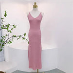 Load image into Gallery viewer, A sleeveless pink knit maxi dress with a V-neckline displayed on a white mannequin in a bright, minimalist room with a small green plant on the left.
