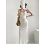 Load image into Gallery viewer, A woman modeling a white knit maxi dress with a V-neck and textured pattern, holding a white Gucci-branded paper cup to her face and carrying a woven straw bag against a minimalist white background.
