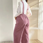 Load image into Gallery viewer, Person wearing pink corduroy overalls standing in a room with a window and blinds.
