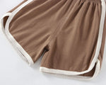 Load image into Gallery viewer, Brown shorts with white trim on a light gray background
